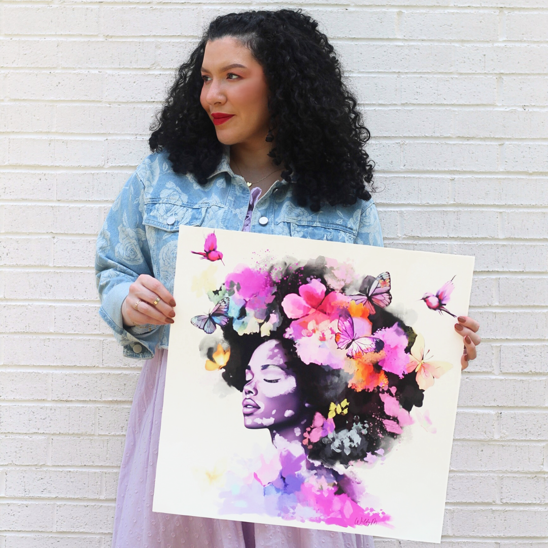 Woman wearing jean jacket holding vibrant artwork featuring woman with vitiligo with butterflies and flowers around her head